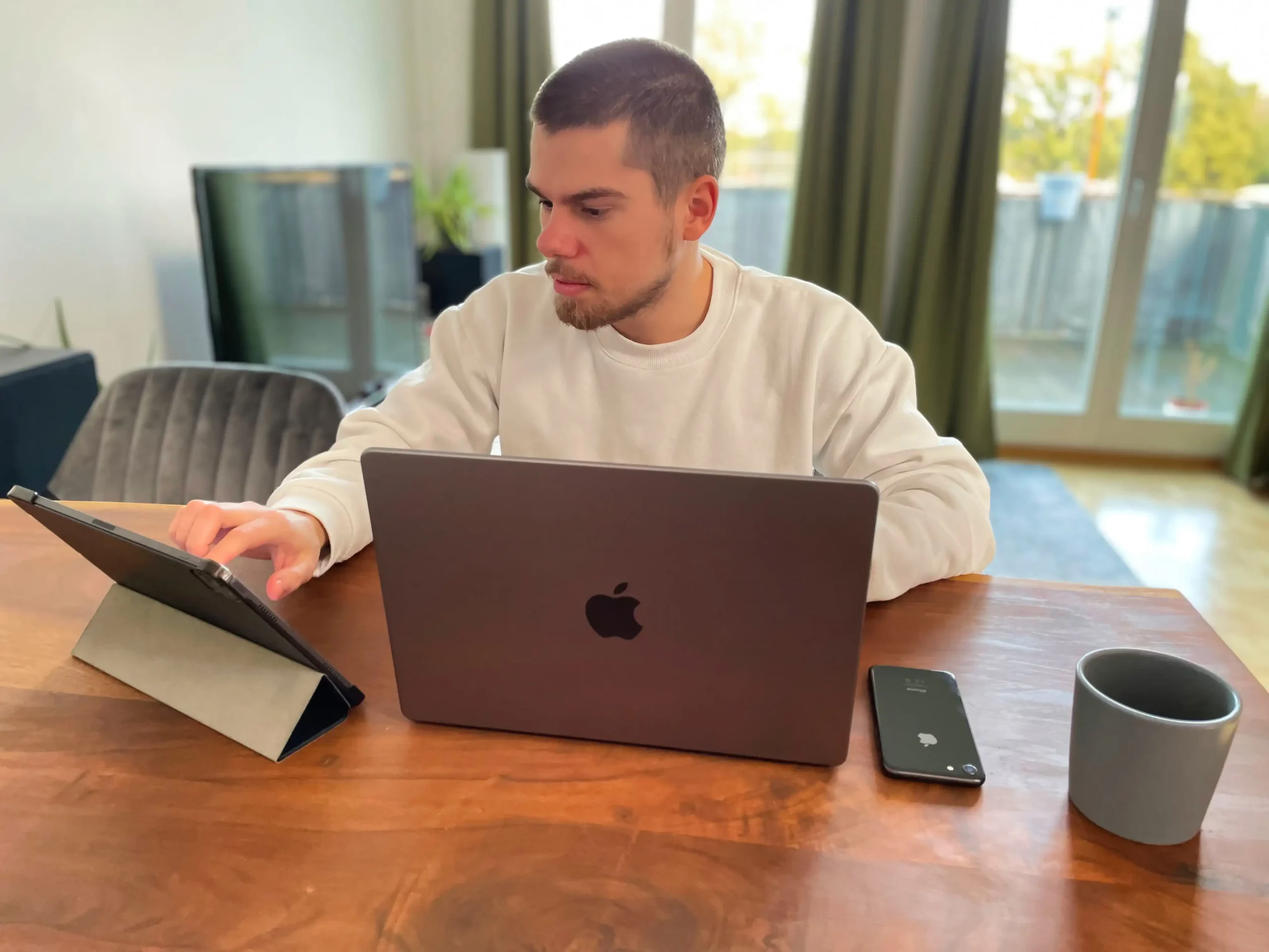 Man using tablet and laptop at home office desk