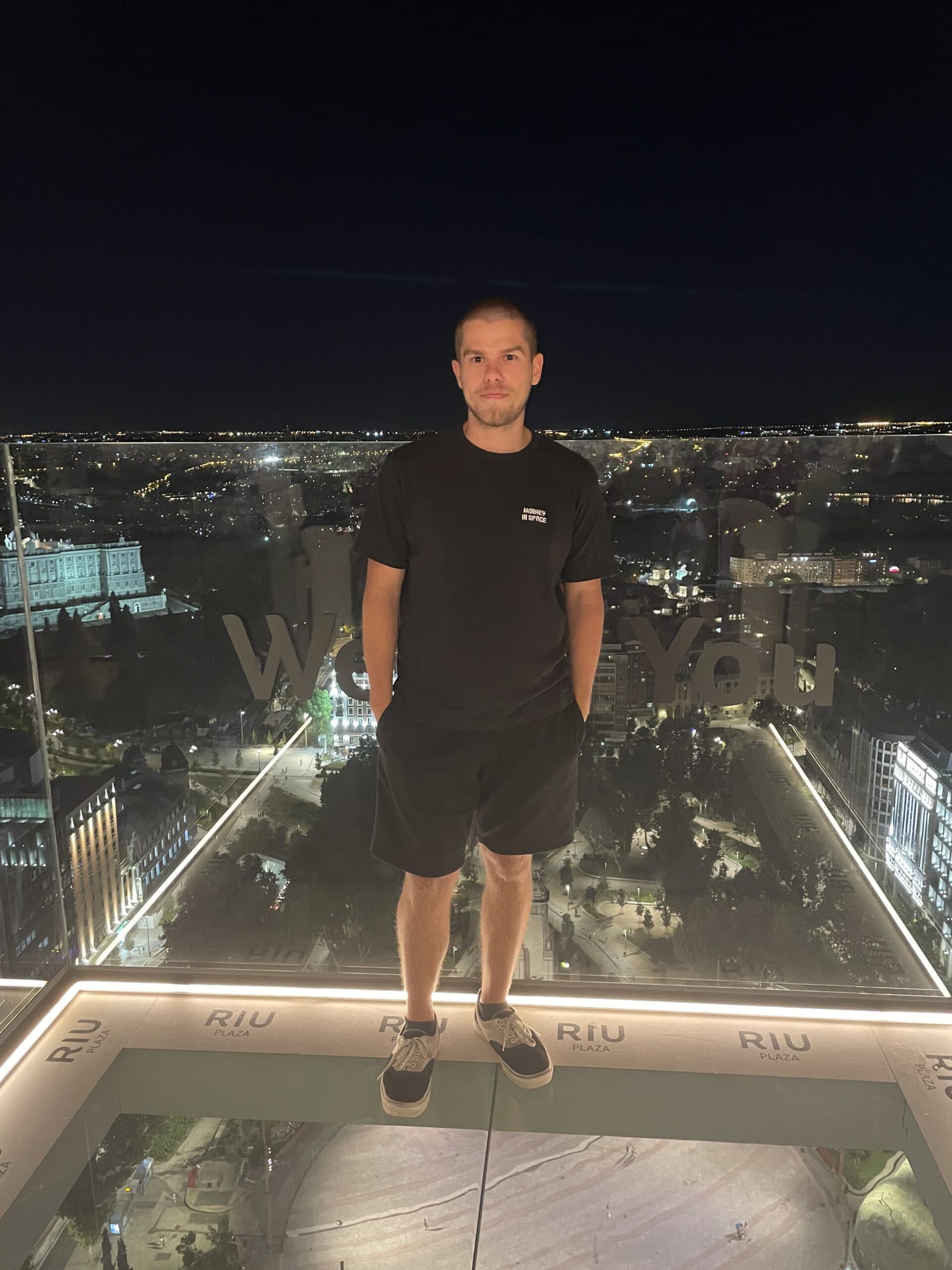 Man standing atop skyscraper at night overlooking city