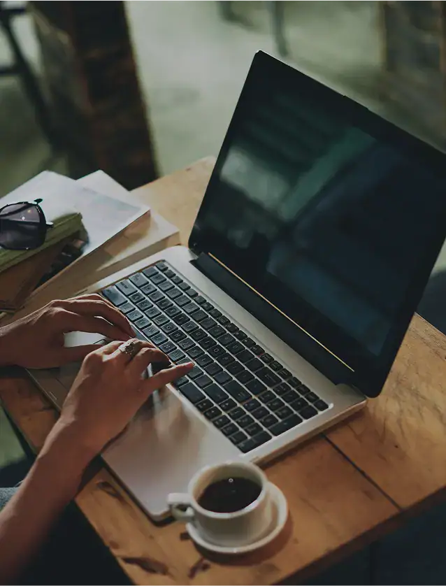 Person typing on laptop with coffee cup nearby
